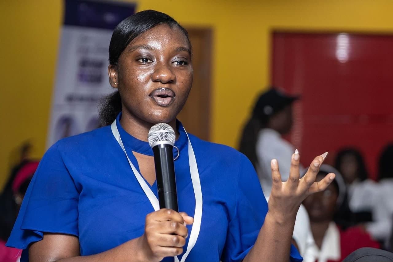 A young woman speaking confidently at the microphone during a GWF masterclass